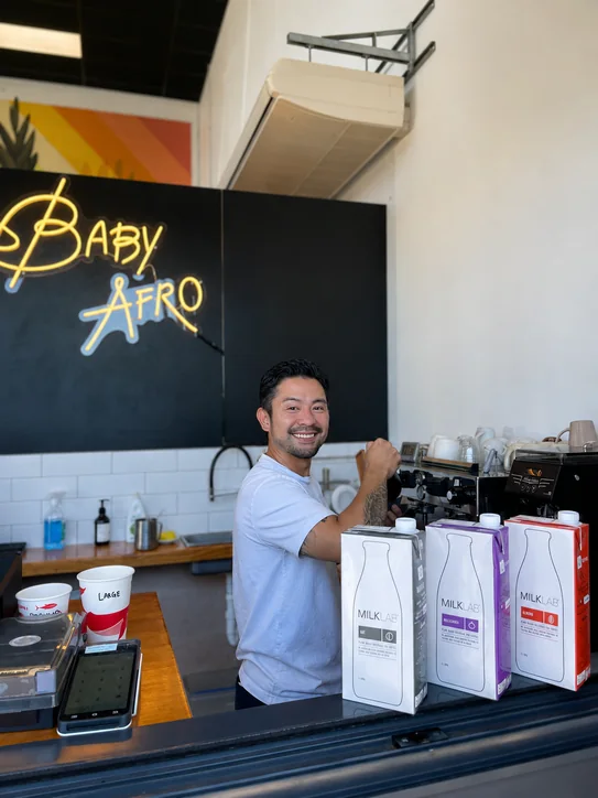A Baby Afro barista behind the coffee bar