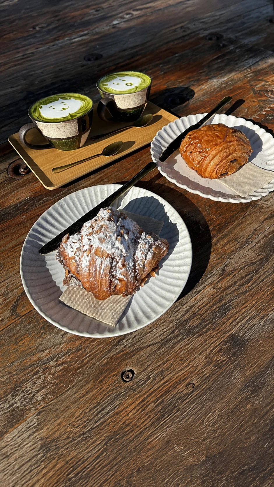 Matcha drinks and a croissant on an outdoor table
