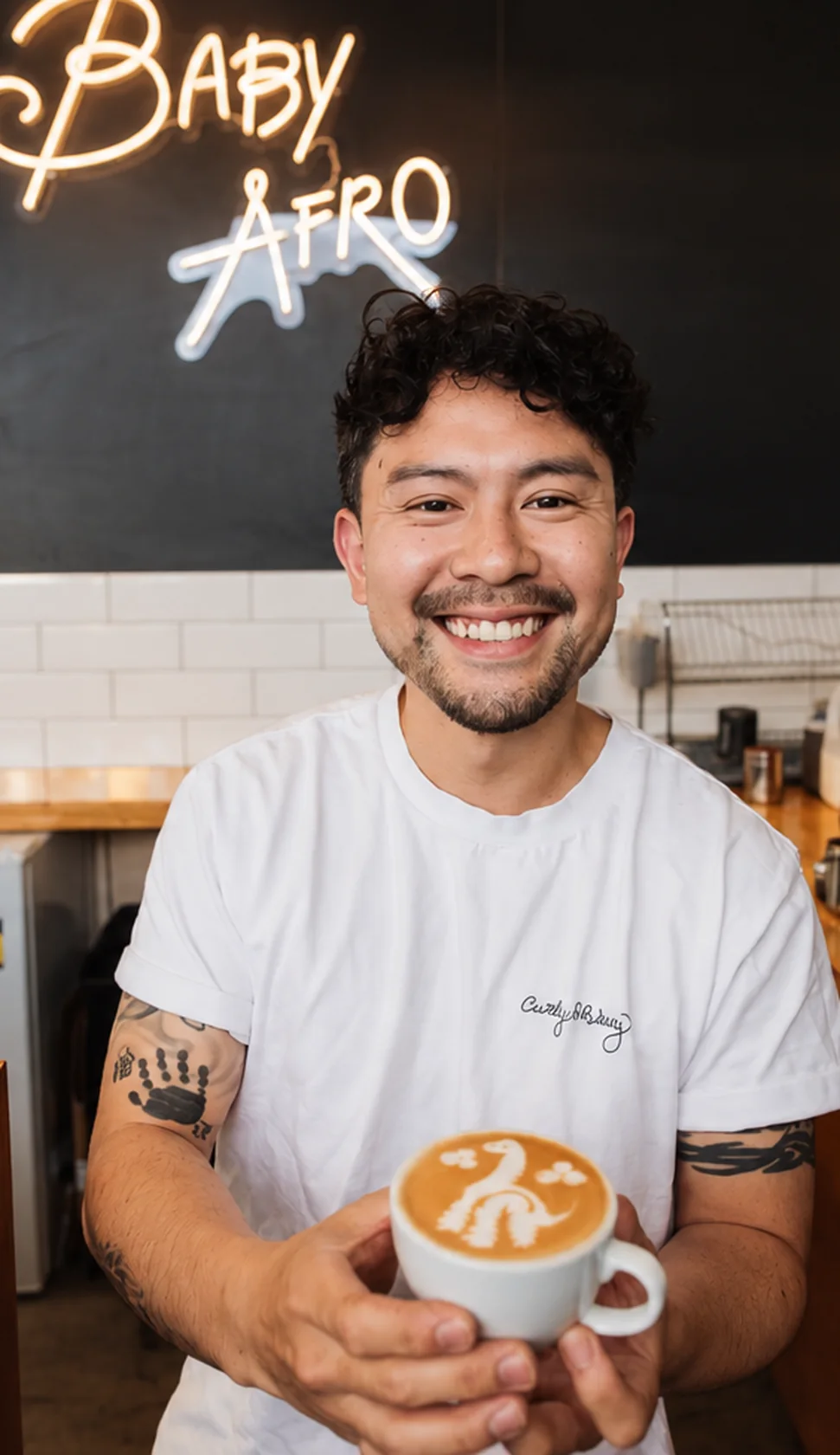 Baby Afro barista holding a finished latte